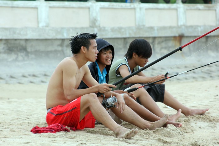 Trong khi đồng đội đều xuống tắm biển thì Văn Quyết đứng trên bờ trổ tài câu cá.